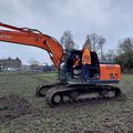 een oranje bulldozer op het grasveld met deel aarde waar gegraven is