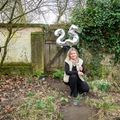 Carien van Boxtel zittend in haar tuin met zilverkleurige balonnen met cijfers 2 en 5