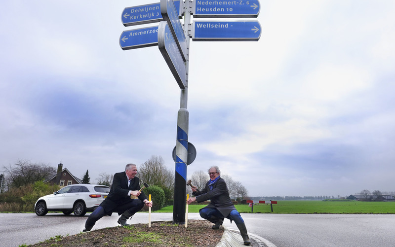 Wethouders Jan-Hein de Vreede van Maasdriel en Gijs van Leeuwen van Zaltbommel slaan piketpaaltje in berm onder wegwijsborden bij Maas-Waalweg