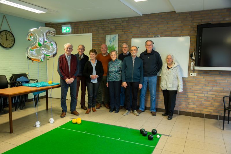 Groepsfoto van de ouderenvereniging in Bruchem met links in beeld zilveren ballonnen die het getal 25 vormen