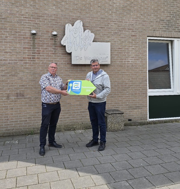 Cornelis Bouman staat voor school Wegwijzer in Nederhemert en krijgt van Wim van der Toorn een bordje met punt met daarop Toekomstvisie Bommelerwaard overhandigd